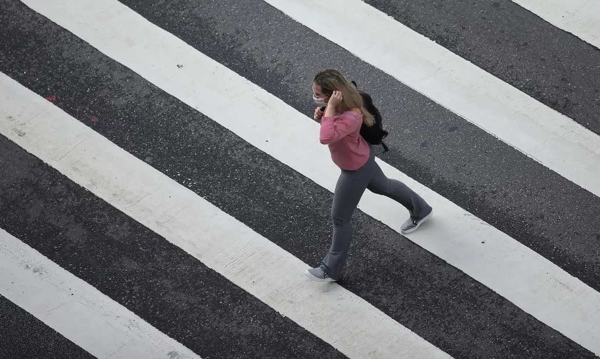 Mulher com máscara de proteção em avenida de São Paulo